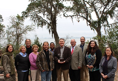 Environmental educator Mark Madden holds the trophy he was awarded by winning the 2015 South Carolina Environmental Awareness Award. He is shown on the shore of Charleston Harbor along with some of his colleagues at Charleston County Parks and Recreation Commission, members of the award planning committee and host agency representatives. (SCDNR photo by Erin Weeks)