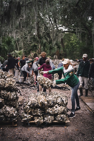 SCORE's Ryan Raiford tosses a bag of recycled oyster shells atop a pile that will be planted on a South Carolina shore later this year. (Photo: Dylan Schmitz)