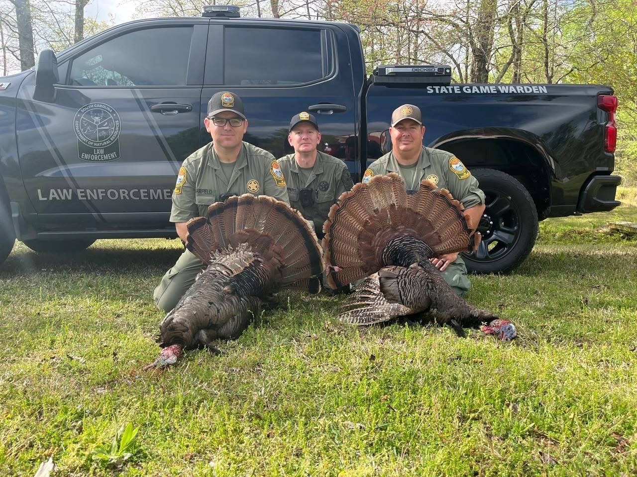 Three SCDNR employees standing with three hunted turkeys
