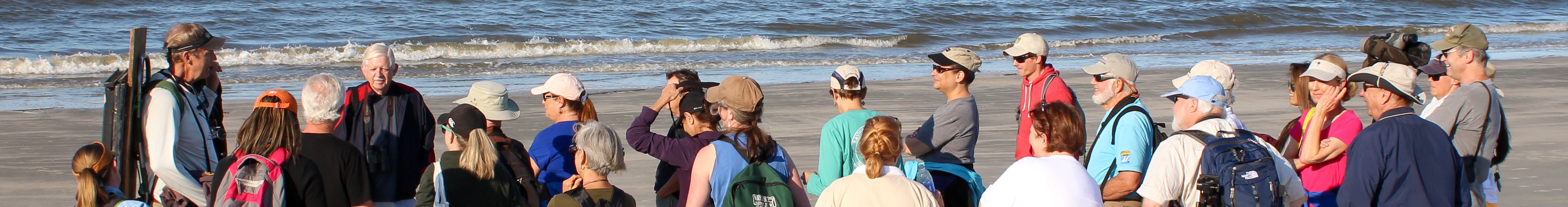 A class on the beach surrounding an instructor